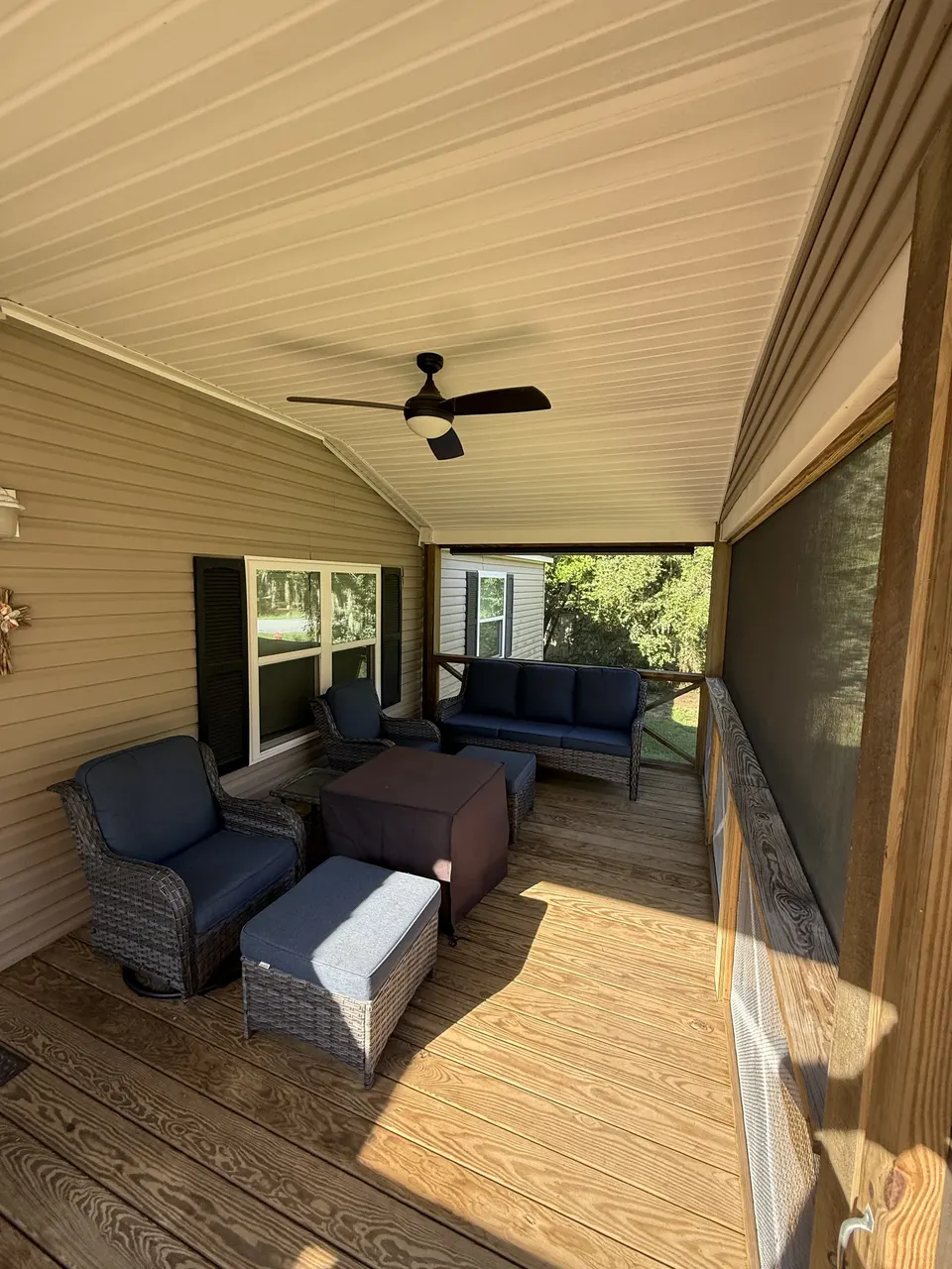 Covered porch seating at Sapelo House with cushioned outdoor chairs and a shaded view of the yard.