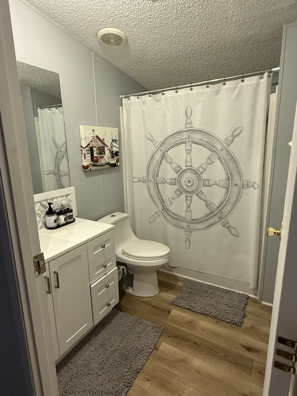 Guest bathroom at Sapelo House with a white vanity, shower curtain, and nautical coastal decor.