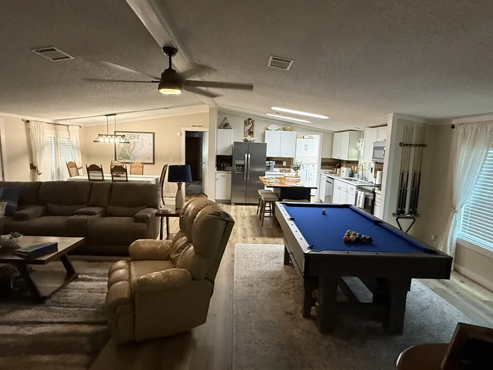 Open-concept living and game area at Sapelo House with a pool table, lounge seating, kitchen, and dining space.
