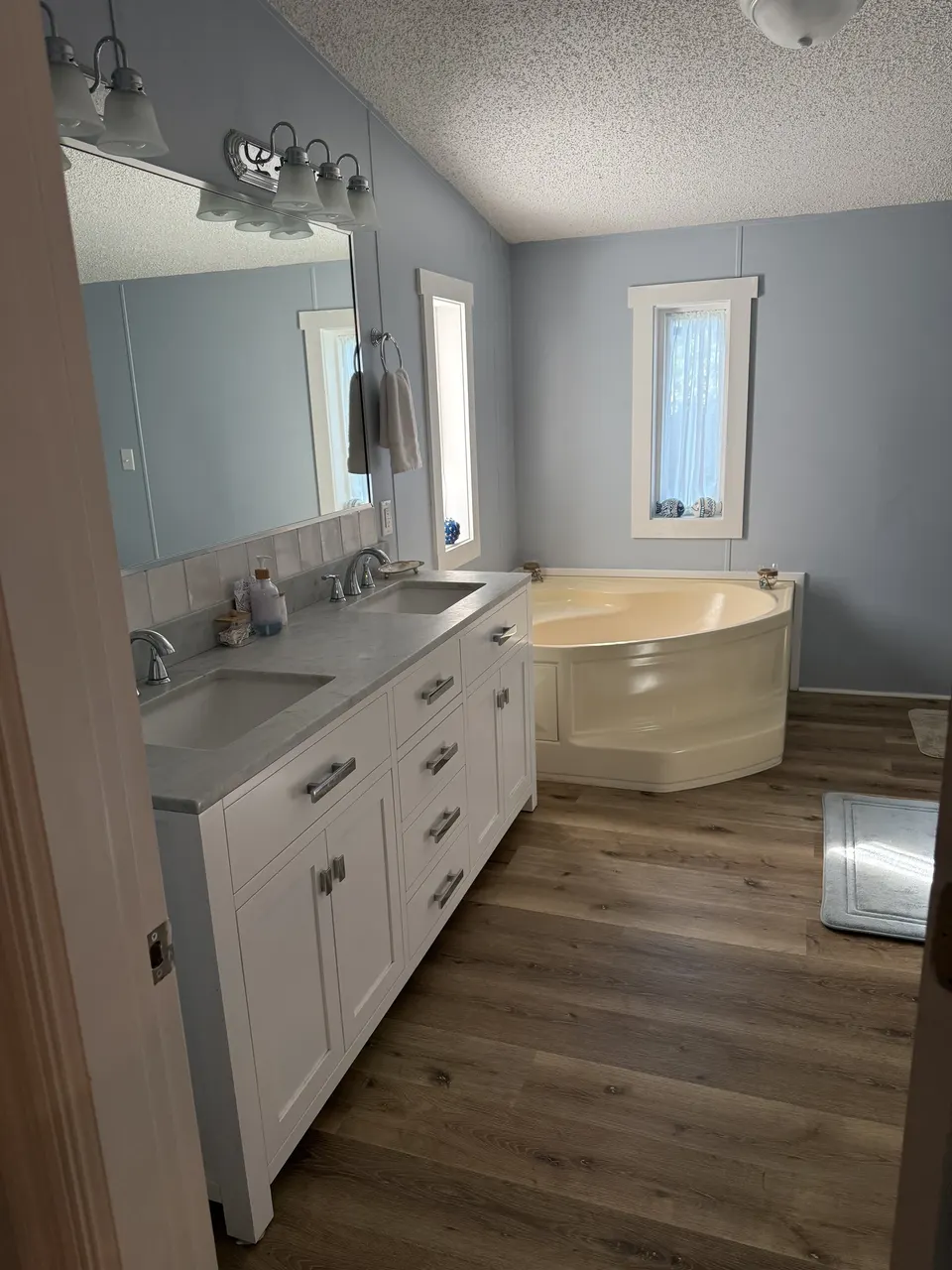 Primary bathroom at Sapelo House with a double vanity, soaking tub, shower, and soft blue walls.